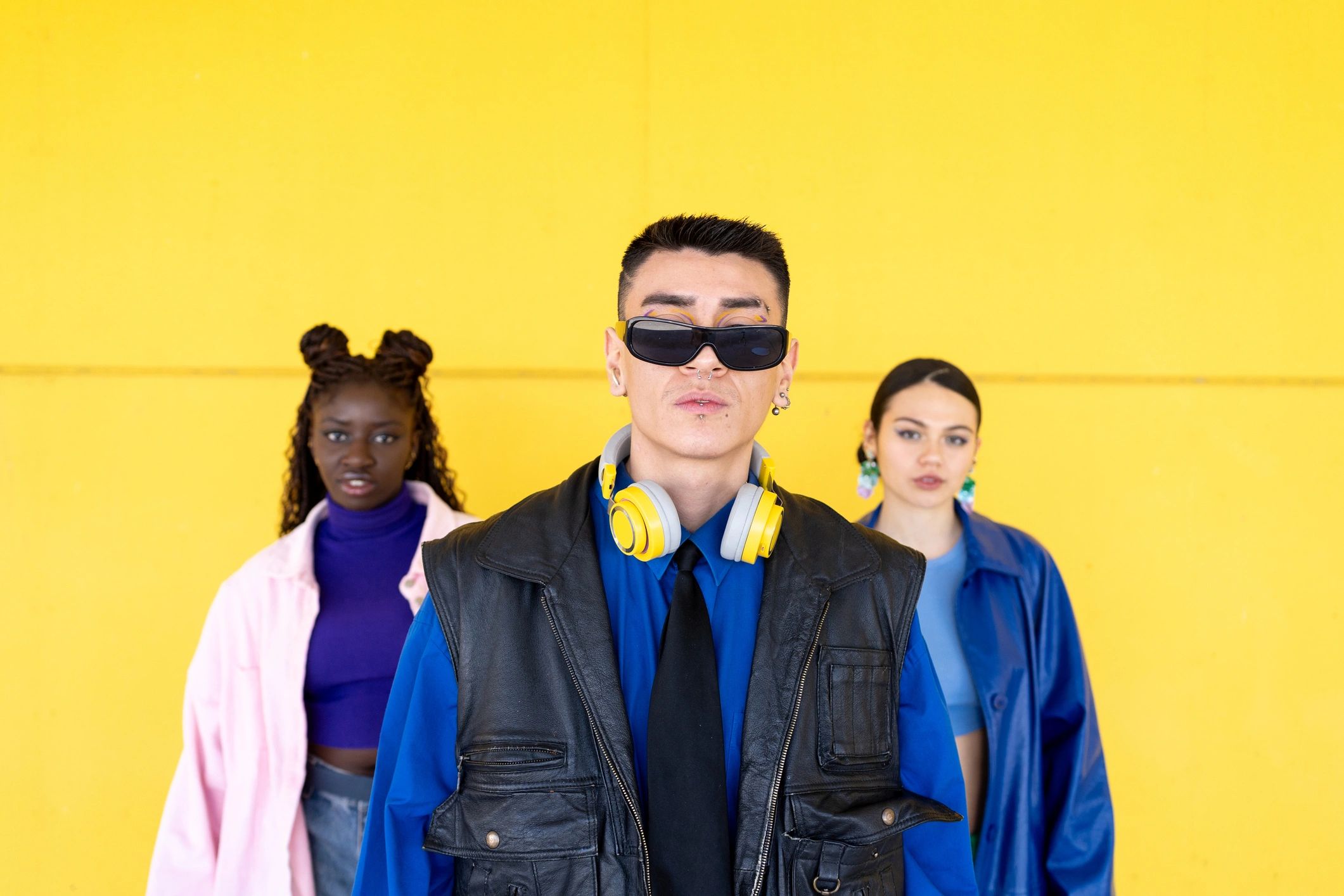 Stylish young people posing against a vibrant yellow wall