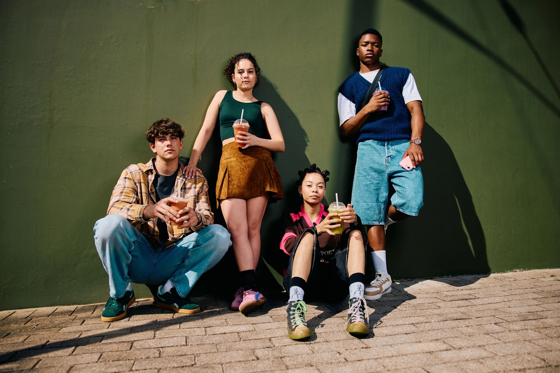 Group of stylish friends outdoors with drinks in a candid fashion moment